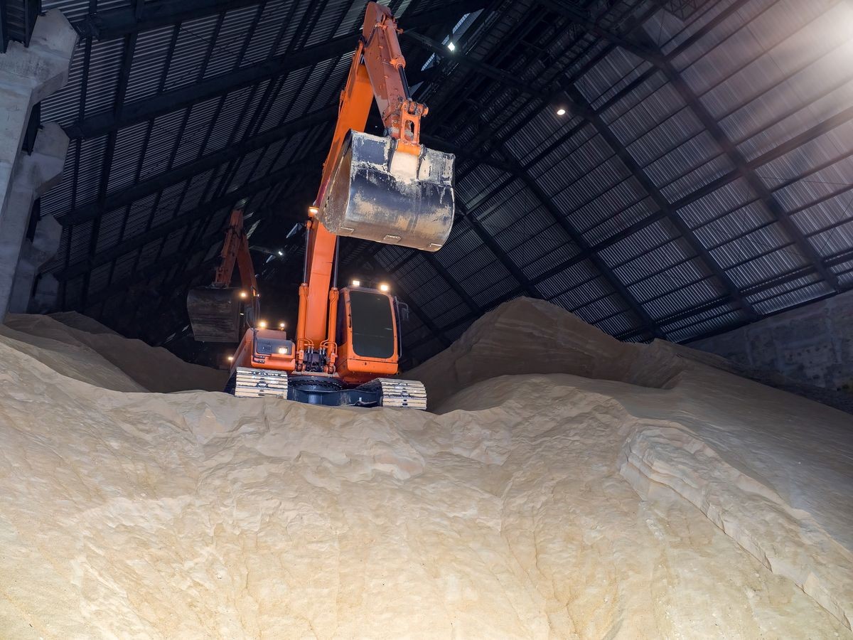 Raw sugar bulk store in bulk warehouse and handling by backhoe.